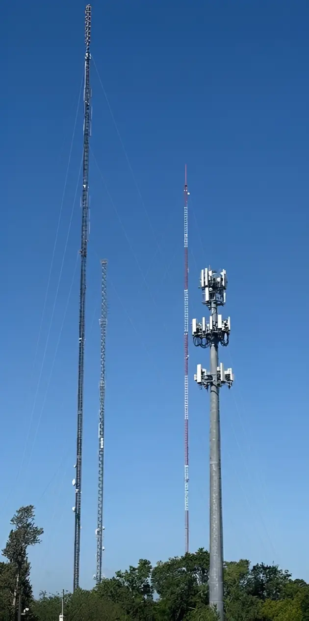 Three cell towers with antennas against sky